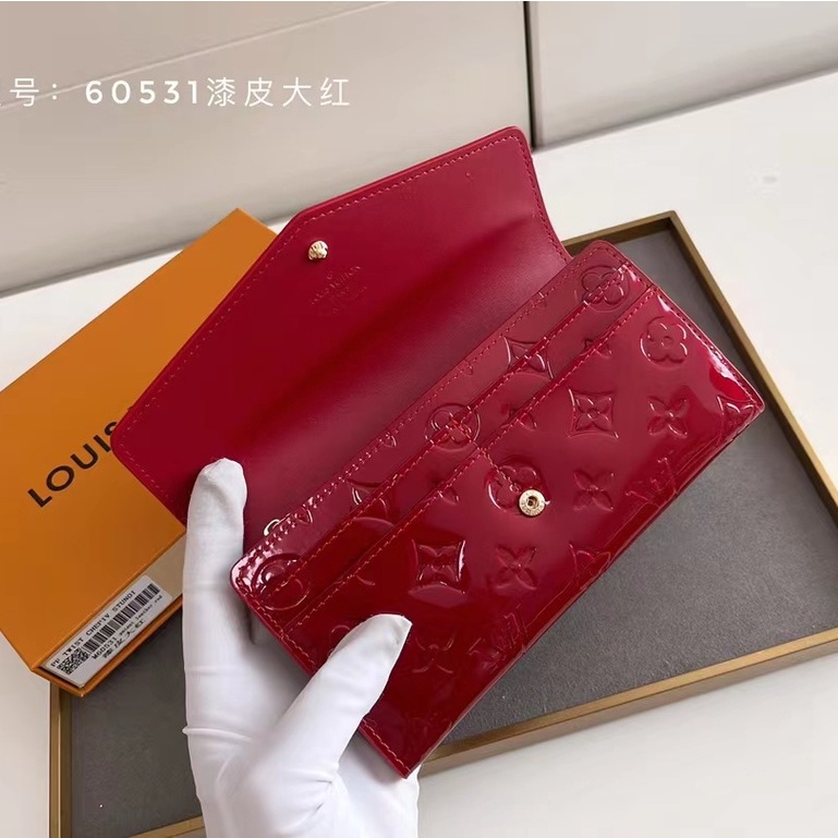 Una cartera roja y marrón dice LOUIS VUITTON con iniciales 'LV', Medidas:  40cm de largo x 22 cm de a